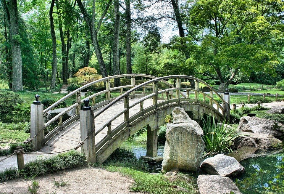 arched wooden footbridge over creek in wooded area
