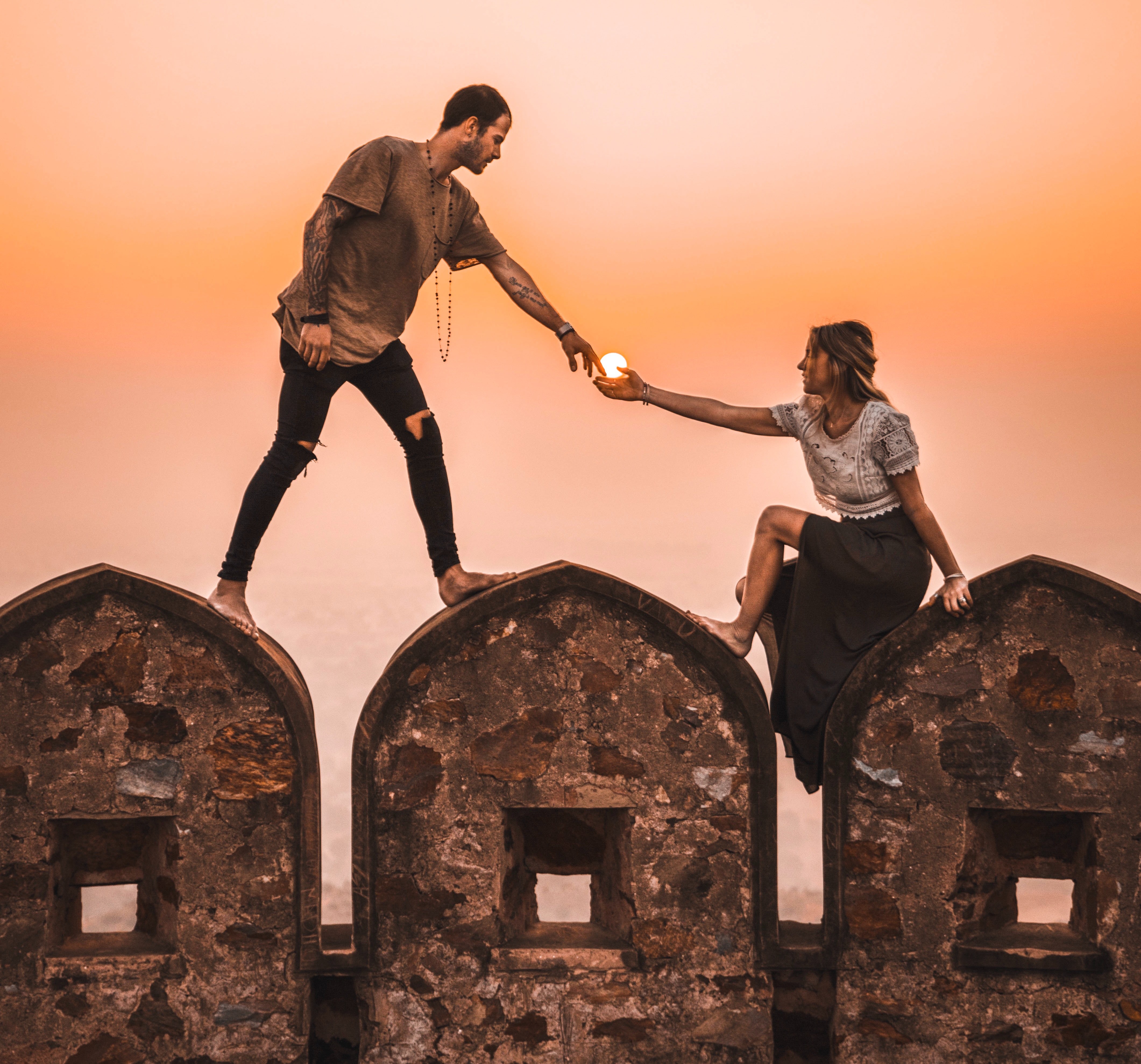 Image of a young man and woman climbing on a structure on a date