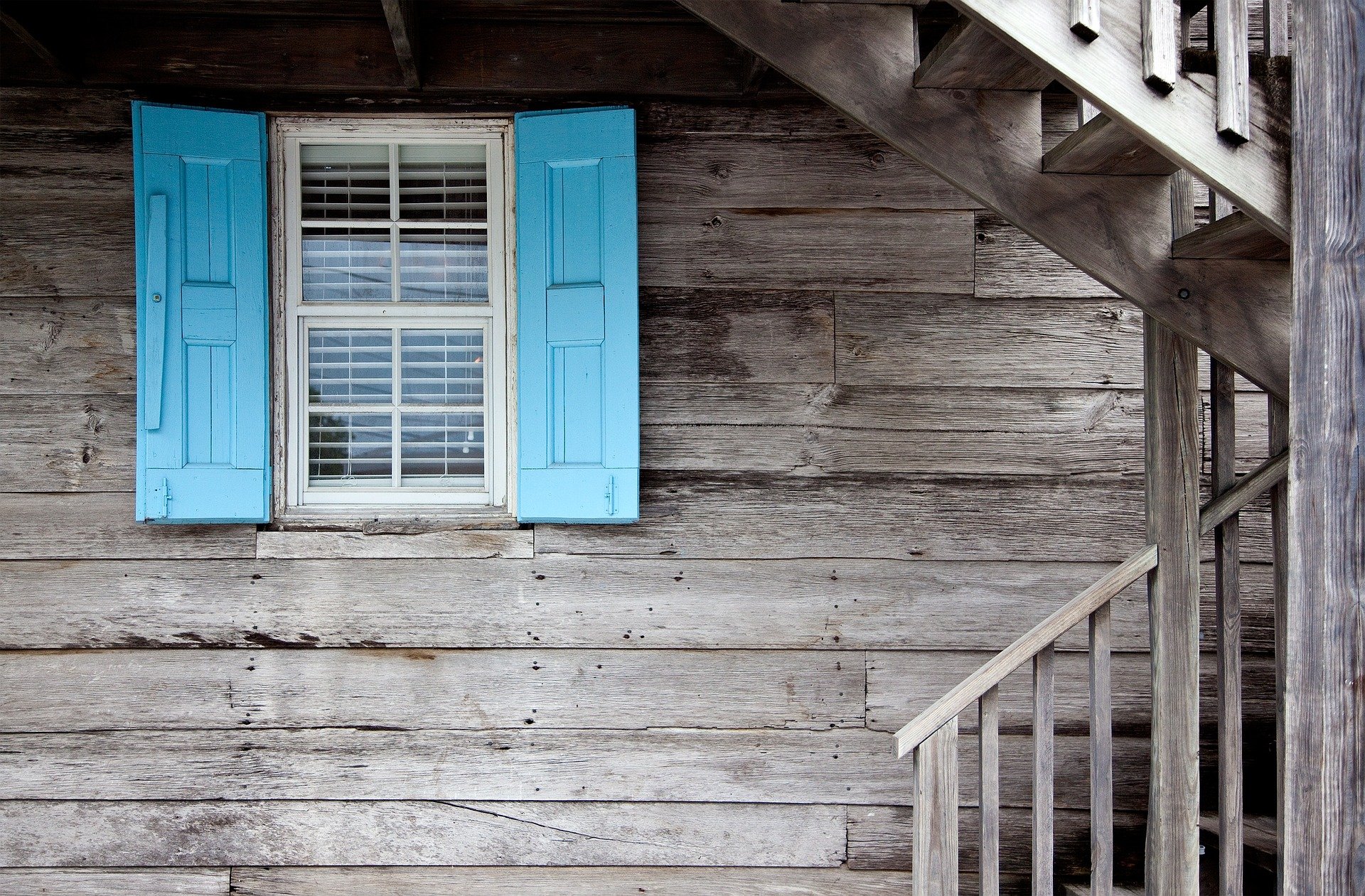 image of barn wood style home with bright blue newly painted window shutters